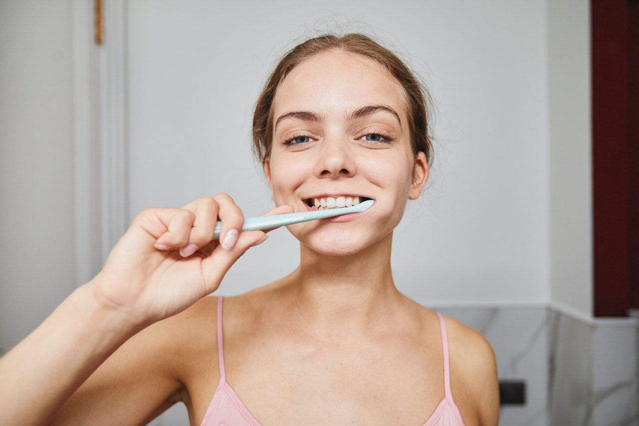 Woman is brushing her teeth gently becuase of fresh tooth piercing