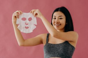 Woman is holding face mask to take are about her face skin condition